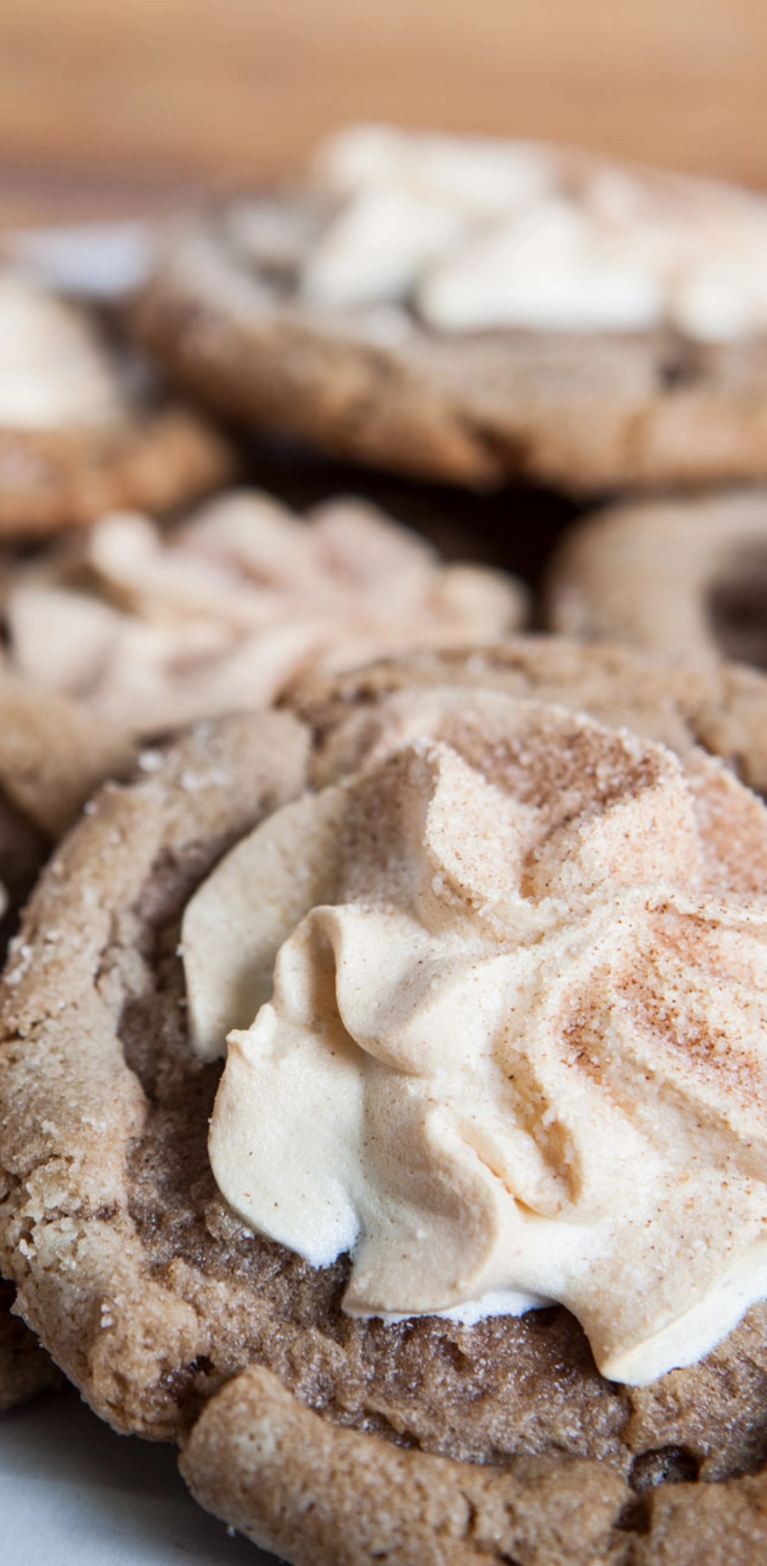 Close-up of baked cookies topped with a dollop of whipped cream and a sprinkle of cinnamon.