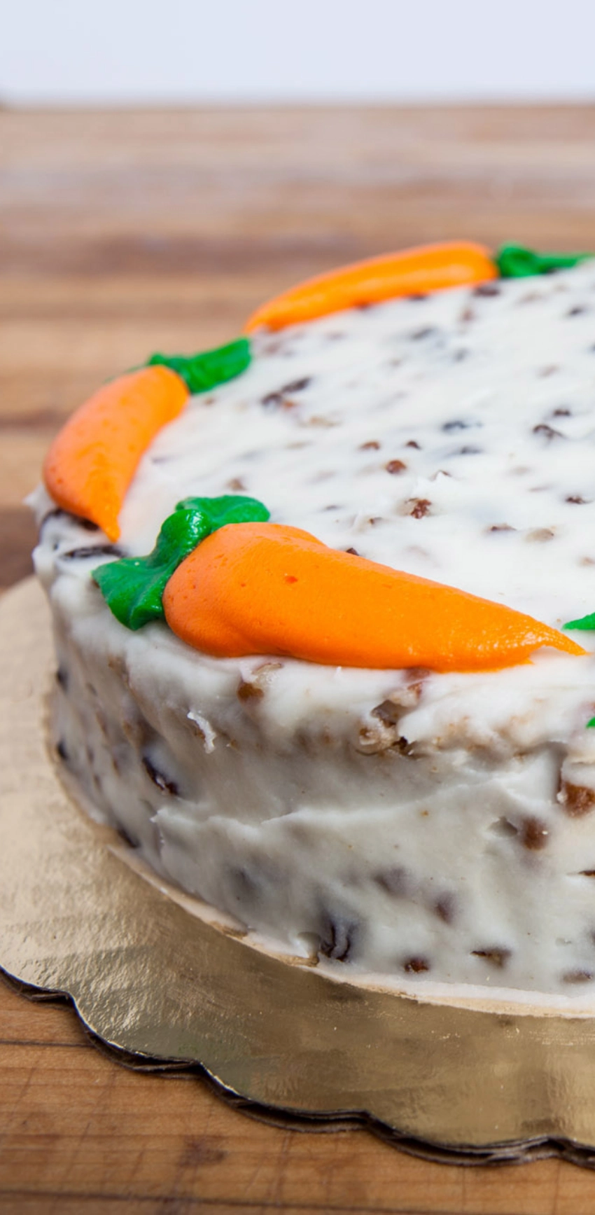 Carrot cake topped with cream cheese frosting and decorated with orange carrot-shaped icing.